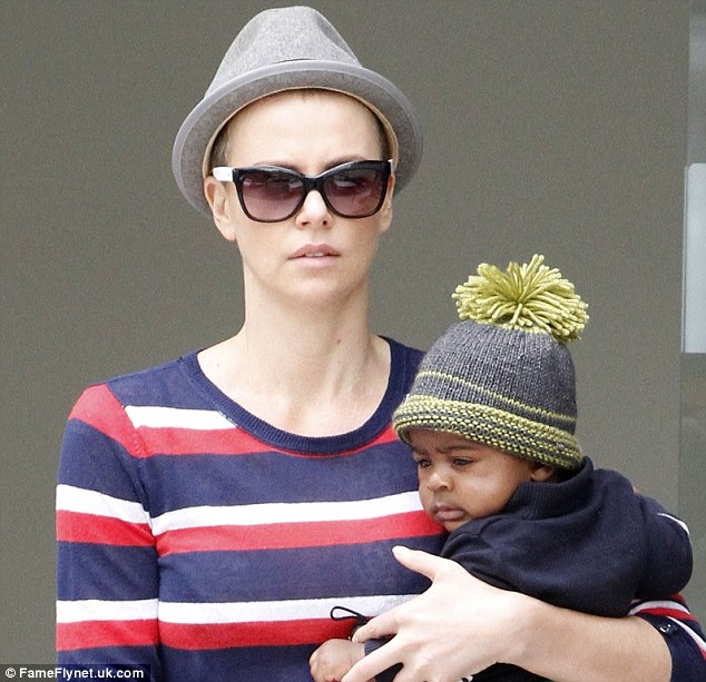 The bald truth: Charlize first stepped out with shaven locks under a pork pie hat in Beverly Hills on Monday with son Jackson