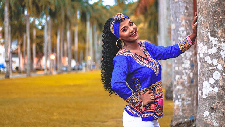 Smiling woman in blue dashiki leans on pole