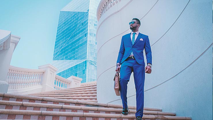 Man in electric blue suit stands on a roof