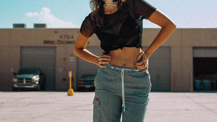 Woman with crop top stands with hands on hips