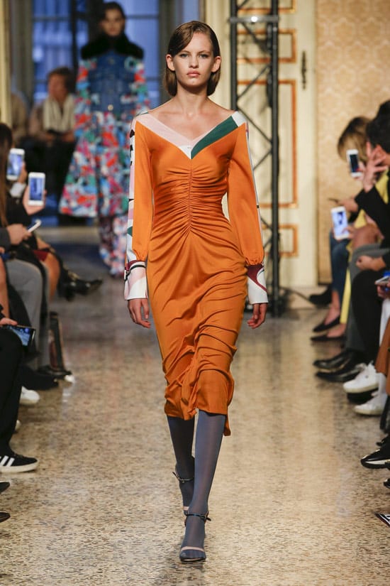 Модель в атласном оранжевом платье с длиными рукавами от Emilio Pucci