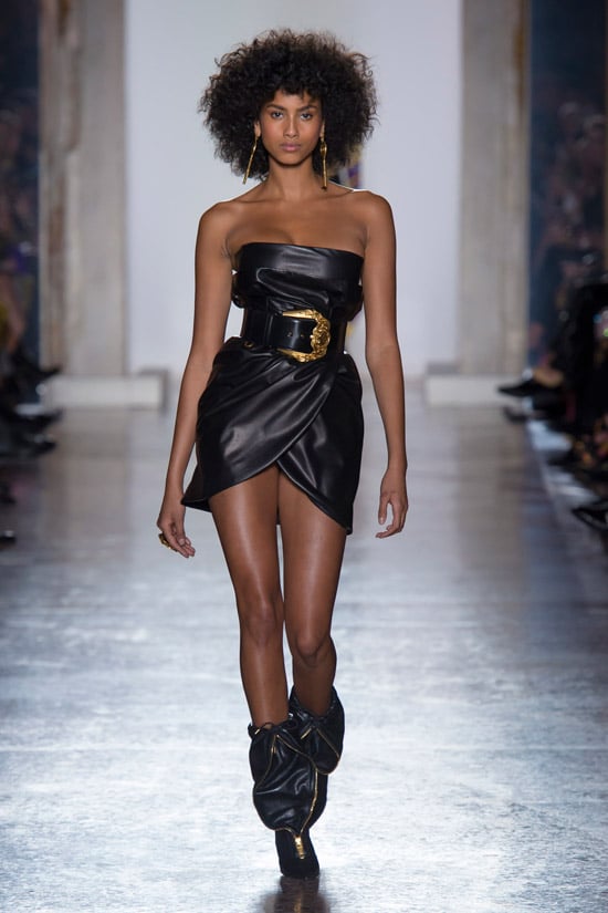 Модель в черном кожаном мини платье с пояом от Versace